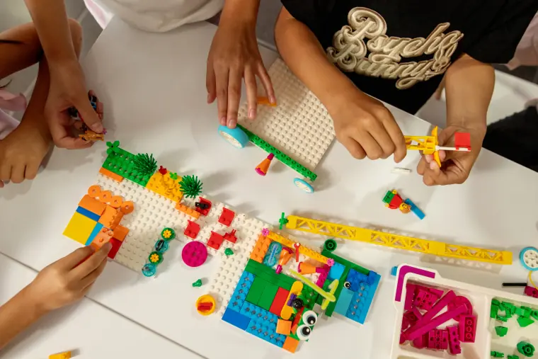 Manos de estudiantes construyendo un proyecto con piezas